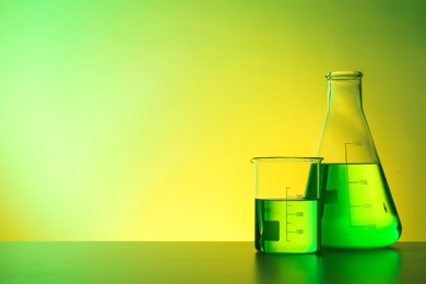 Photo of Chemistry laboratory glassware with samples on table against color background