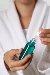 Woman with bottle of cosmetic serum and dropper, closeup