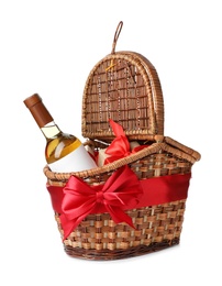 Photo of Festive basket with bottle of wine and gift on white background