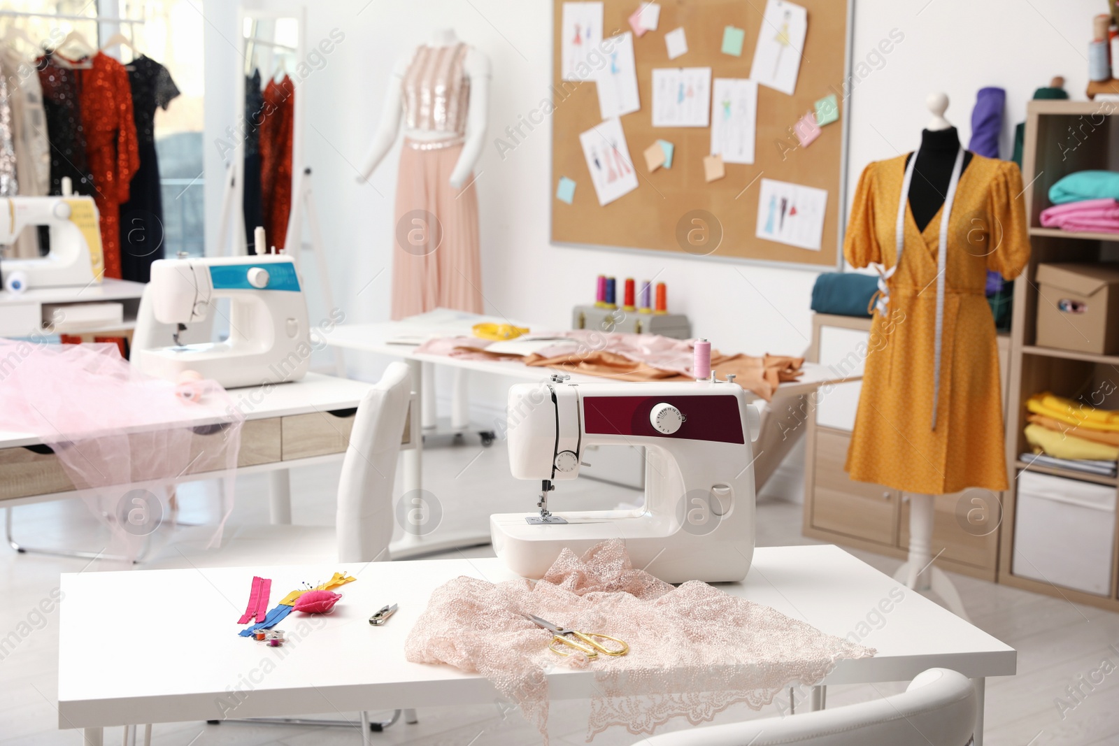 Photo of Dressmaking workshop interior with stylish female clothes and equipment