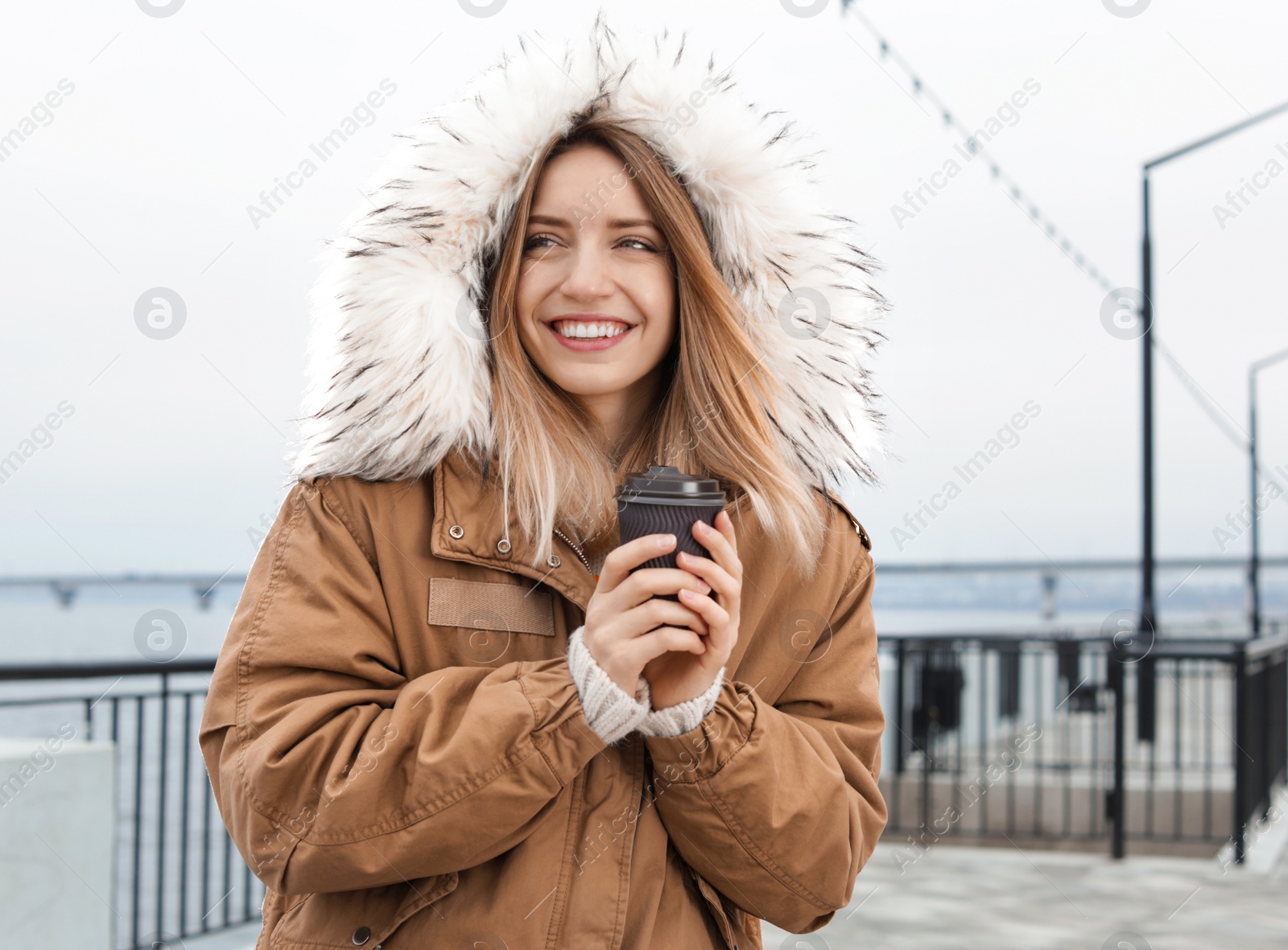 Photo of Young woman with cup of coffee walking outdoors. Space for text