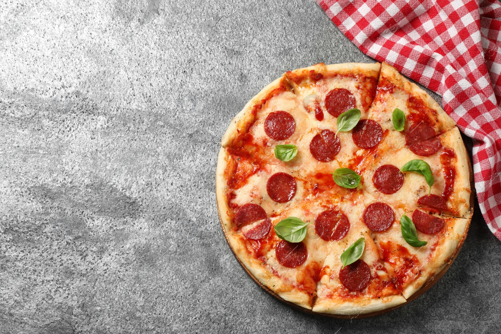 Photo of Hot delicious pepperoni pizza on grey table, top view. Space for text