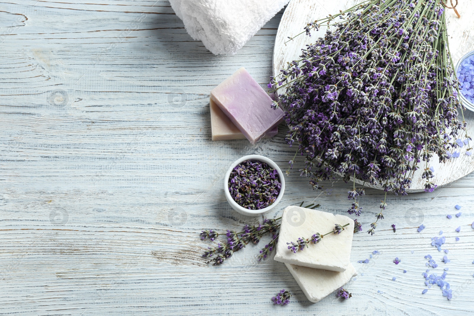 Photo of Flat lay composition of handmade soap bars with lavender flowers on white wooden background. Space for text