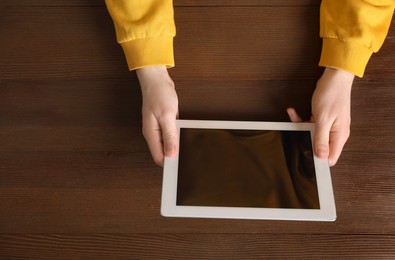 Photo of Man working with tablet at wooden table, top view. Space for text
