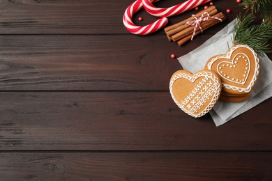 Flat lay composition with tasty heart shaped gingerbread cookies and Christmas decor on wooden table, space for text