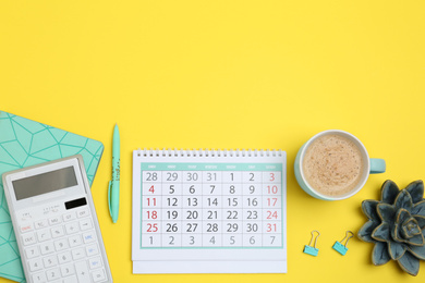Flat lay composition with calendar and cup of coffee on yellow background. Space for text