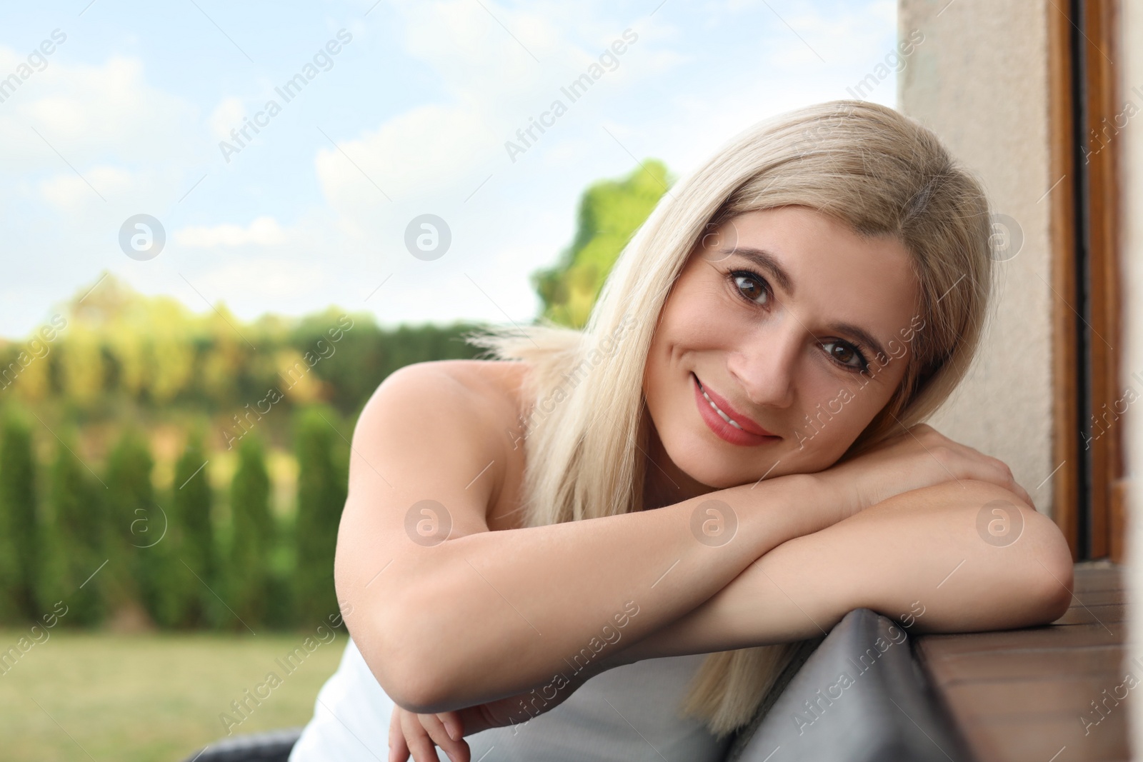 Photo of Portrait of beautiful woman sitting near house in yard, space for text