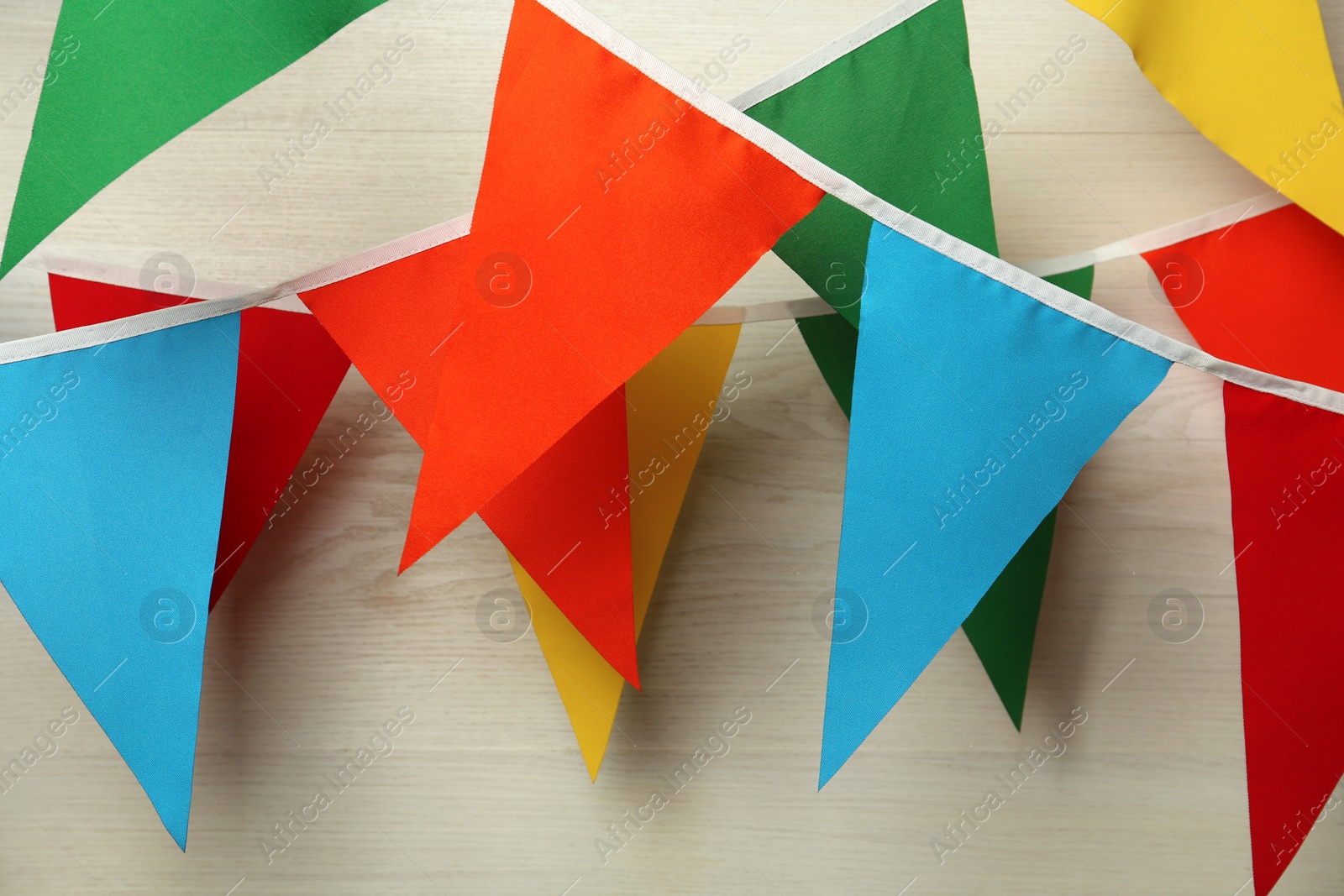 Photo of Buntings with colorful triangular flags on white wooden background