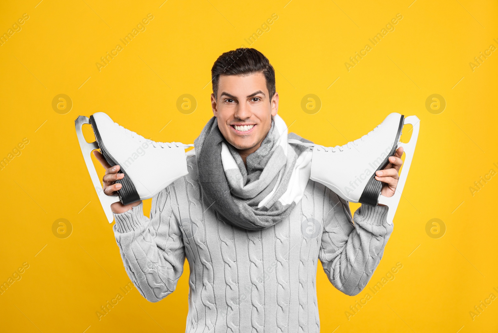 Photo of Happy man with ice skates on yellow background