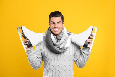 Photo of Happy man with ice skates on yellow background