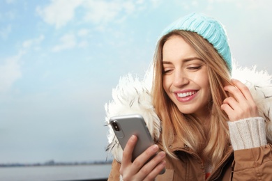 Photo of Young woman using mobile phone outdoors. Space for text