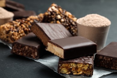 Photo of Different tasty energy bars and protein powder on black table, closeup