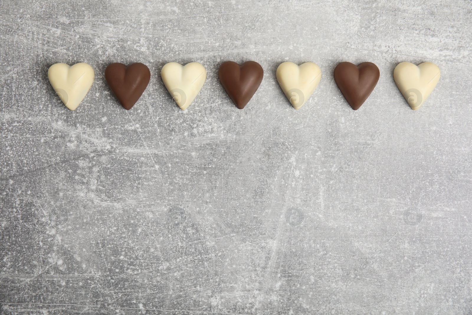 Photo of Tasty heart shaped chocolate candies on light grey table, flat lay with space for text. Happy Valentine's day