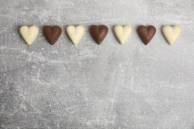 Tasty heart shaped chocolate candies on light grey table, flat lay with space for text. Happy Valentine's day