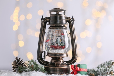 Photo of Snow globe in vintage lantern and Christmas decor against blurred festive lights