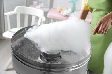 Woman making cotton candy using modern machine indoors, closeup