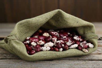 Overturned sack with dry kidney beans on old wooden table, closeup