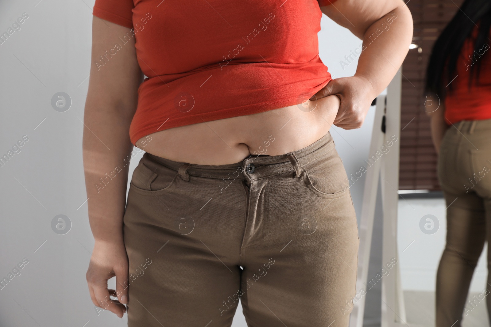 Photo of Overweight woman in tight shirt and trousers at home, closeup