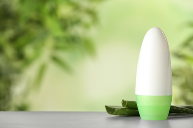 Photo of Deodorant container and aloe vera on white wooden table against blurred background. Space for text