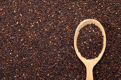 Photo of Raw black quinoa seeds with spoon as background, top view. Space for text