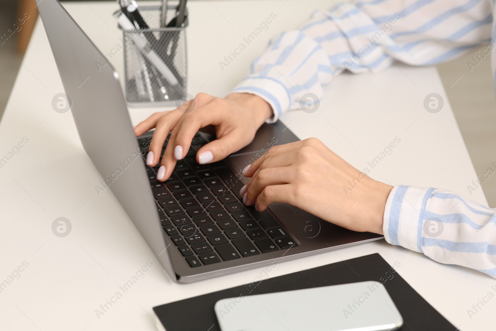 Photo of Woman working with laptop at white desk, closeup