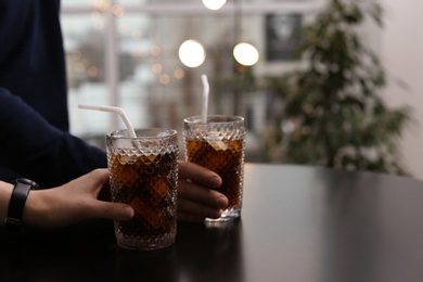 Photo of Couple with glasses of cold cola at table in cafe, closeup. Space for text