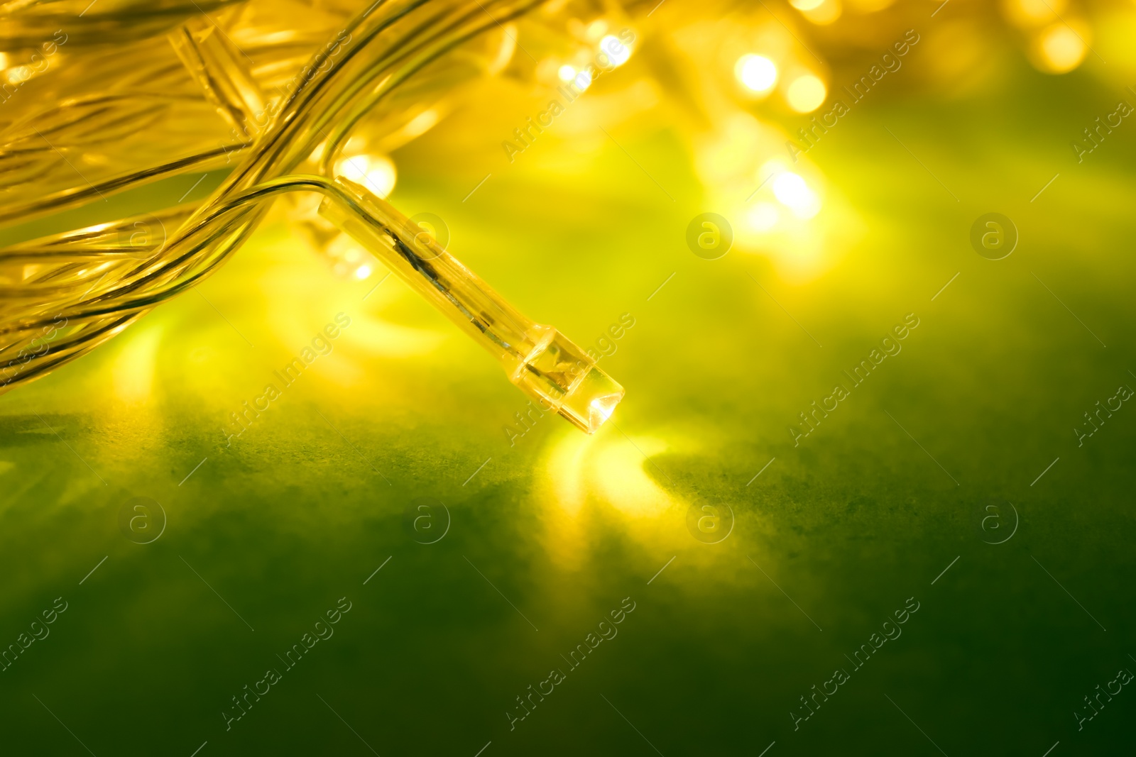 Photo of Glowing Christmas lights on green background, closeup