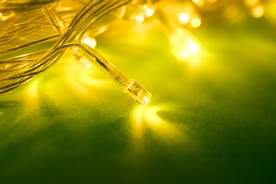 Photo of Glowing Christmas lights on green background, closeup