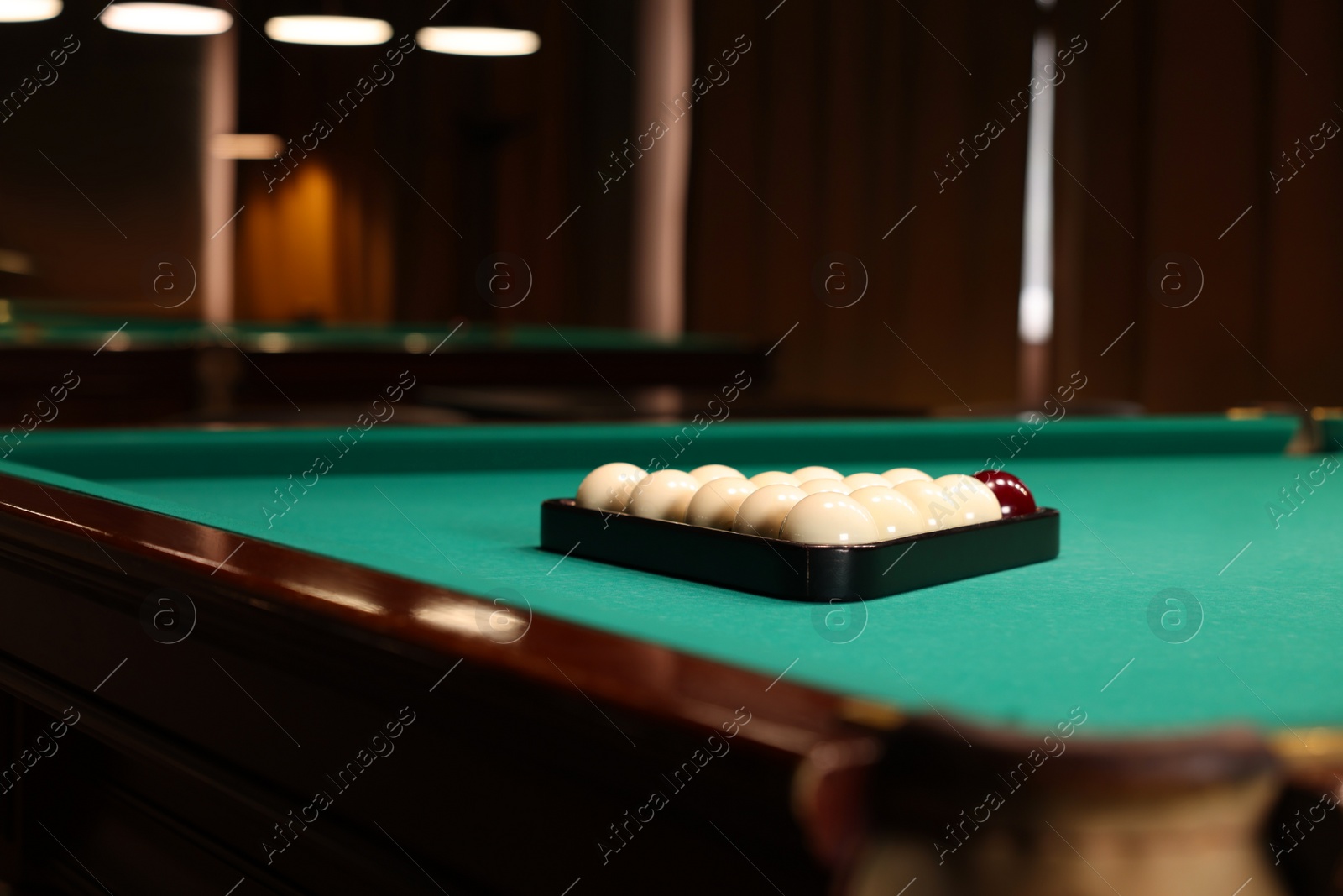 Photo of Billiard balls in triangle rack on green table indoors, space for text