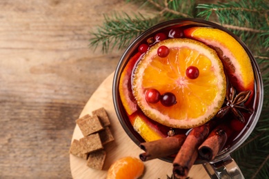 Glass cup of tasty mulled wine on wooden table, flat lay