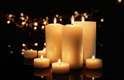 Wax candles burning against blurred lights in darkness