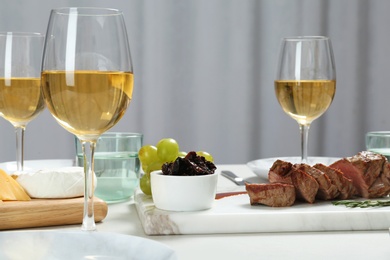 Photo of Tasty steak and glasses of white wine served on table