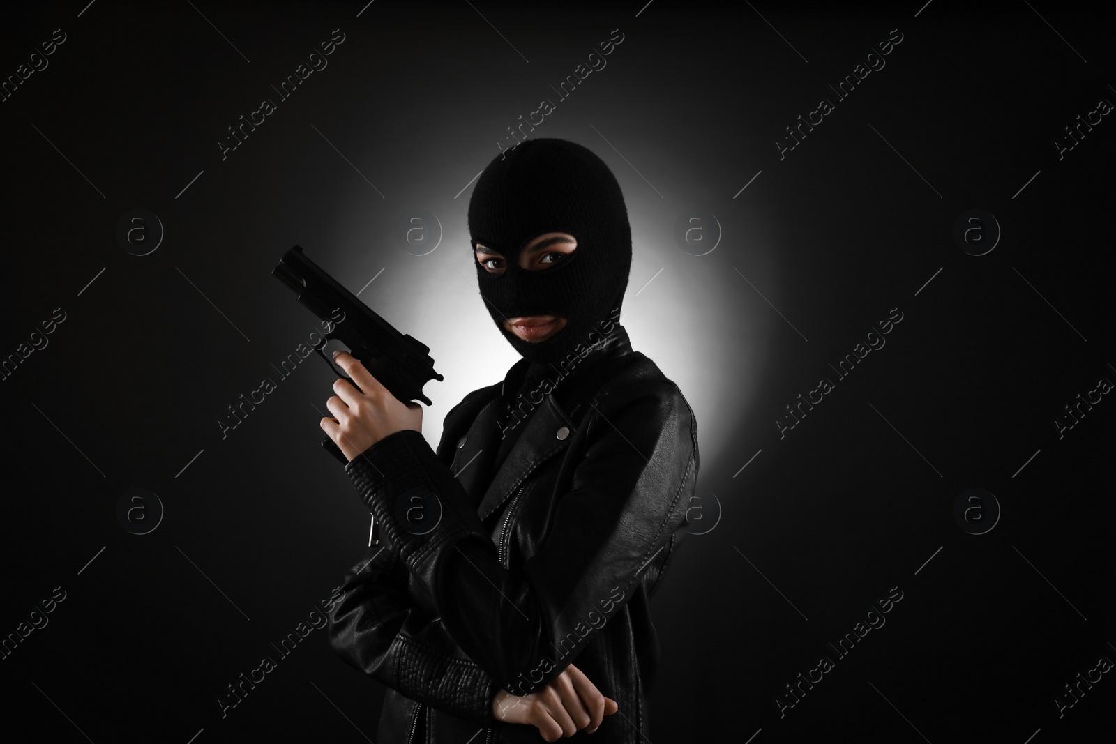 Photo of Woman wearing knitted balaclava with gun on black background