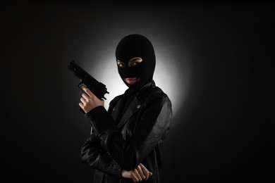 Photo of Woman wearing knitted balaclava with gun on black background