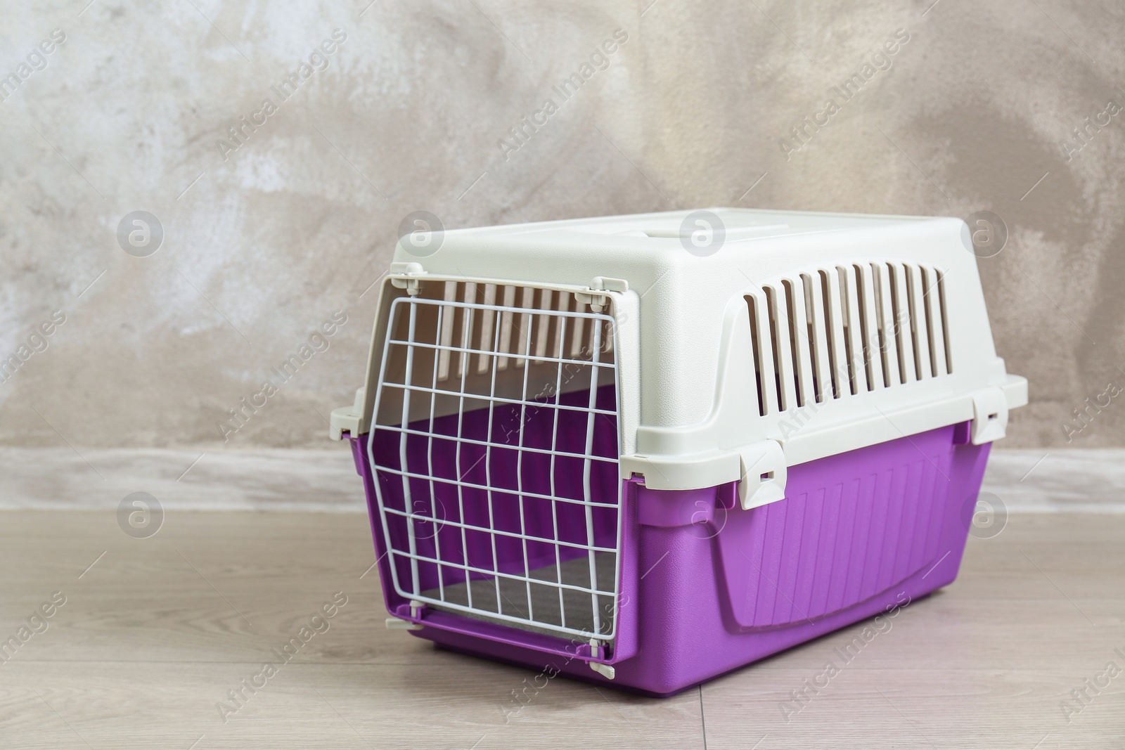 Photo of Violet pet carrier on floor near beige wall, space for text