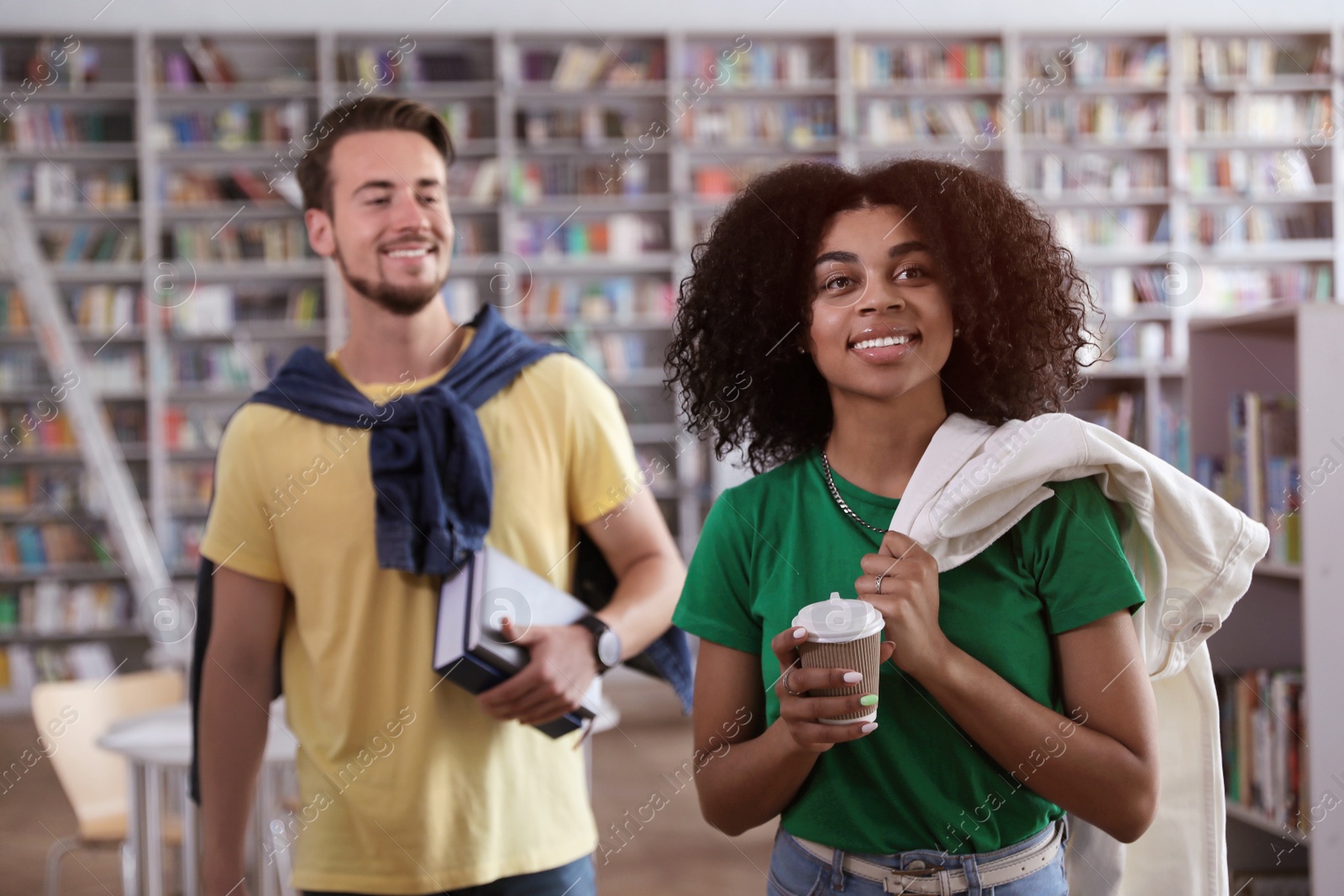 Photo of Happy young people with books in library