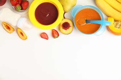 Baby food in bowls and fresh ingredients on white table, flat lay. Space for text