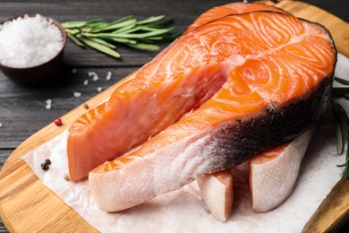 Fresh salmon steaks with spices on black wooden table