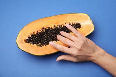 Photo of Young woman touching half of papaya on blue background, top view. Sex concept