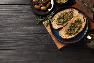 Photo of Tasty bruschettas with pesto and rosemary on black wooden table, flat lay. Space for text