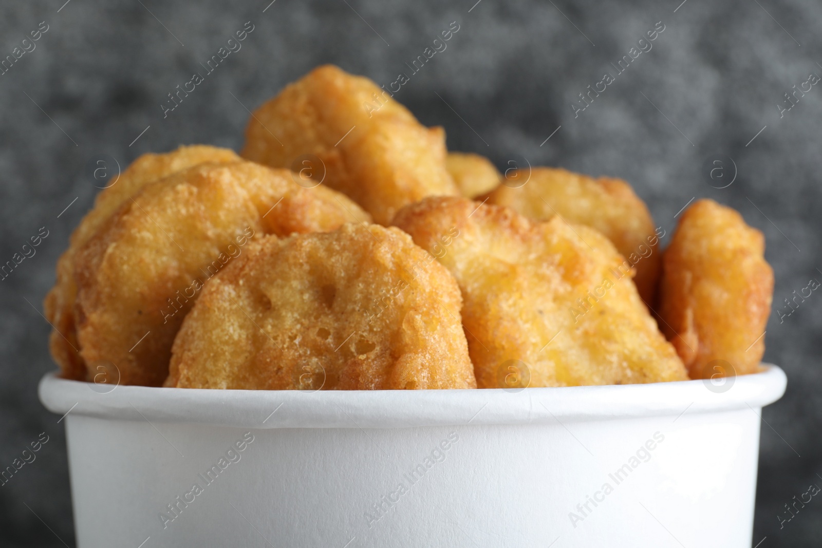 Photo of Bucket with tasty chicken nuggets on grey background, closeup