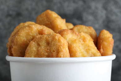 Photo of Bucket with tasty chicken nuggets on grey background, closeup