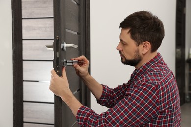 Handyman changing core of door lock indoors