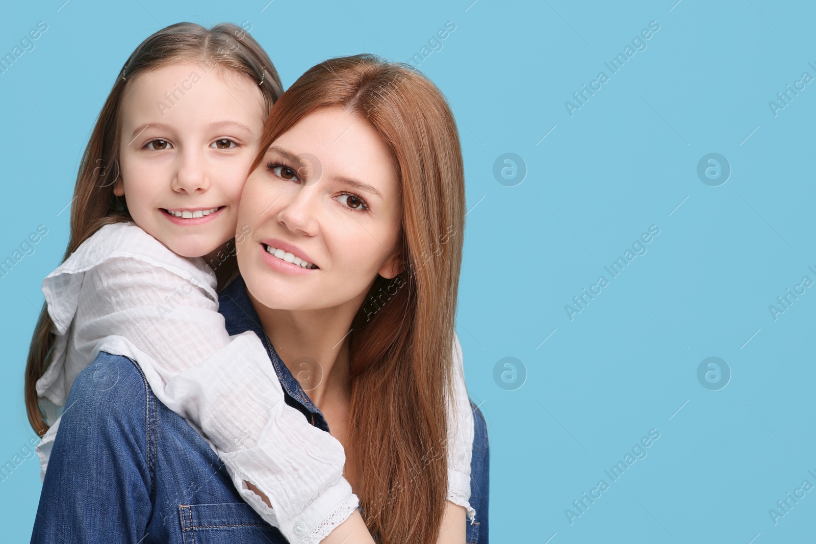 Photo of Portrait of happy mother and her cute daughter on light blue background. Space for text