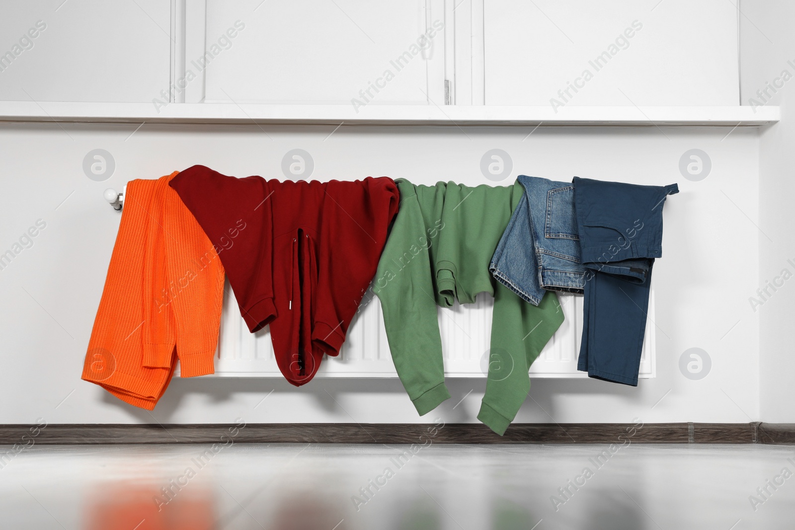 Photo of Clean clothes hanging on white radiator in room