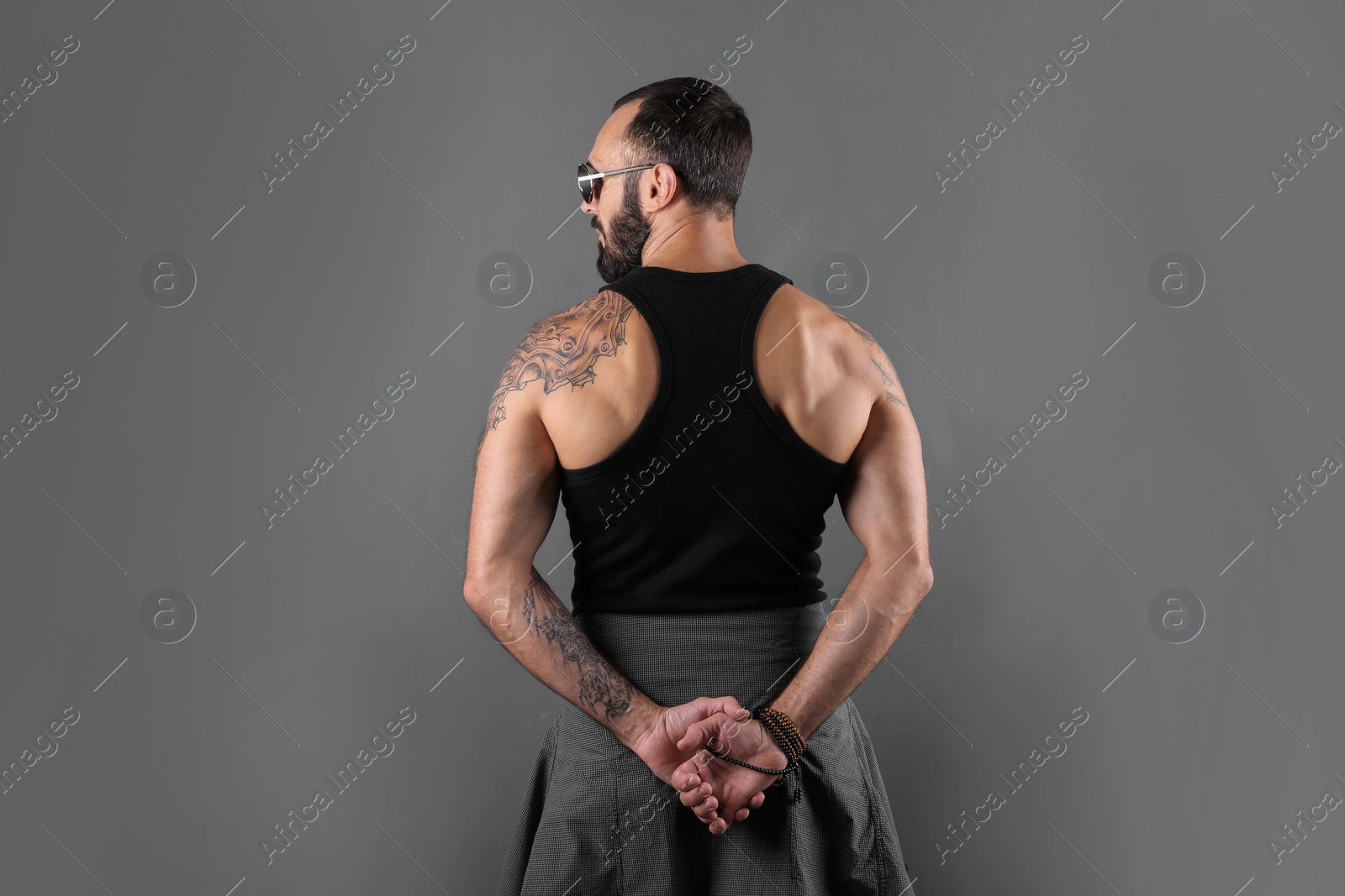 Photo of Attractive tattooed man in stylish clothes on grey background