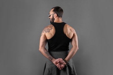 Photo of Attractive tattooed man in stylish clothes on grey background