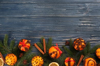 Flat lay composition with pomander balls made of fresh tangerines and cloves on blue wooden table, space for text