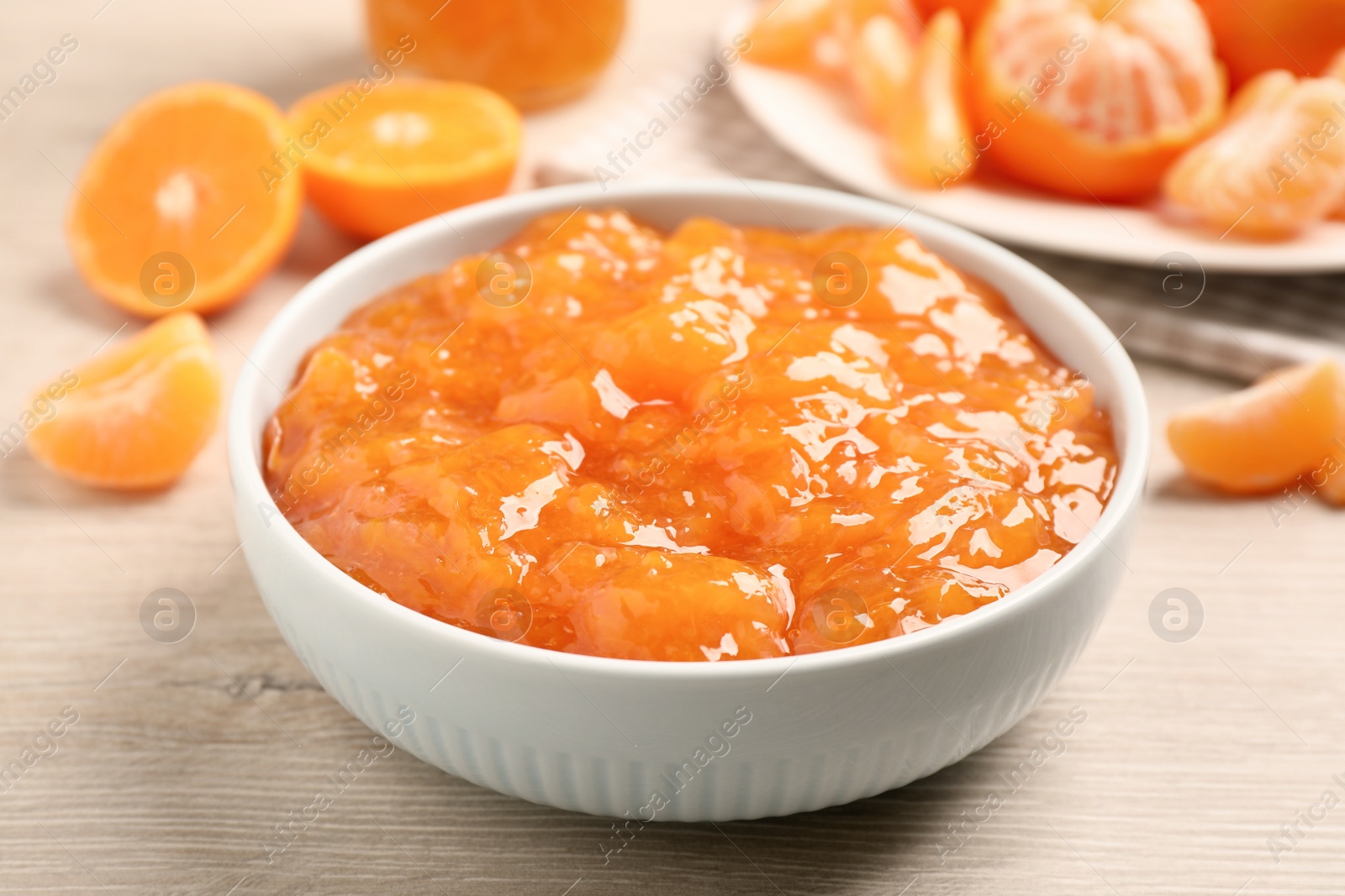 Photo of Delicious tangerine jam on wooden table, closeup