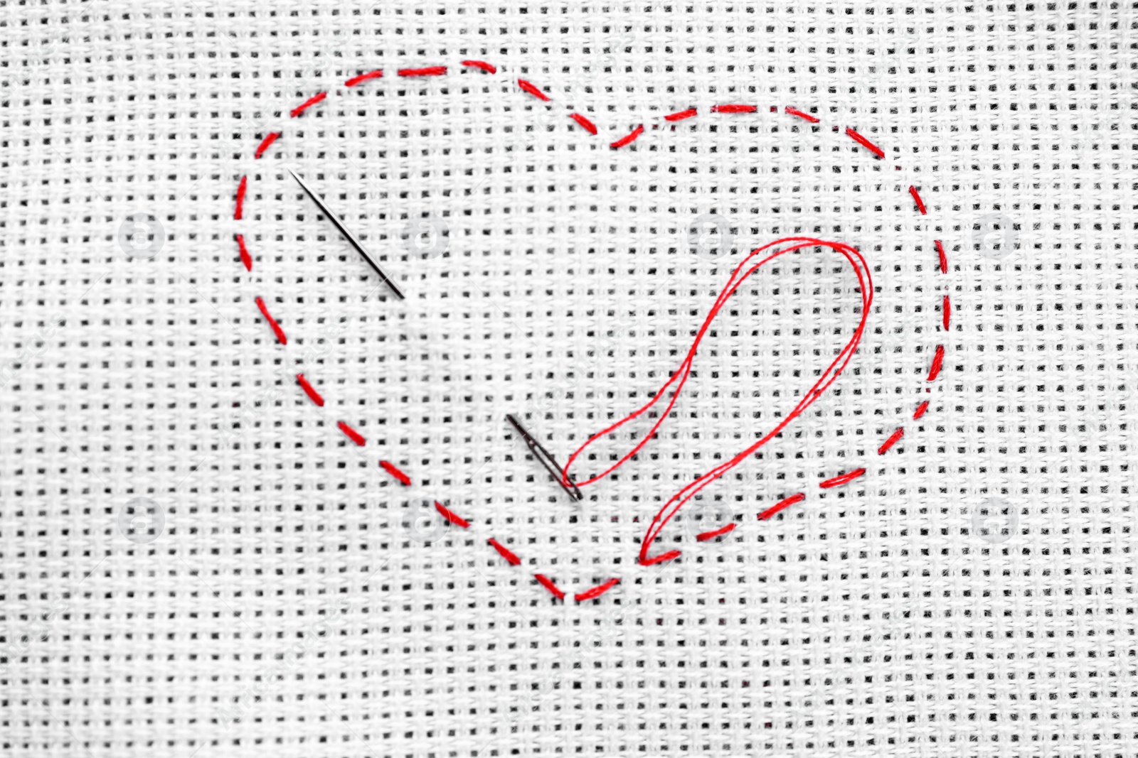 Photo of Canvas with embroidered heart and needle as background, top view